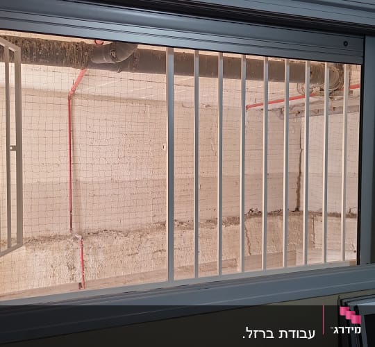 מסגרת חלון עם סורגים פתוחים וקיר בטון